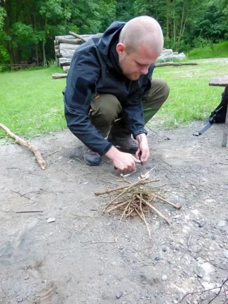 Feuerstahl erzeugt Funken auf Zunder in einem Holzstapel