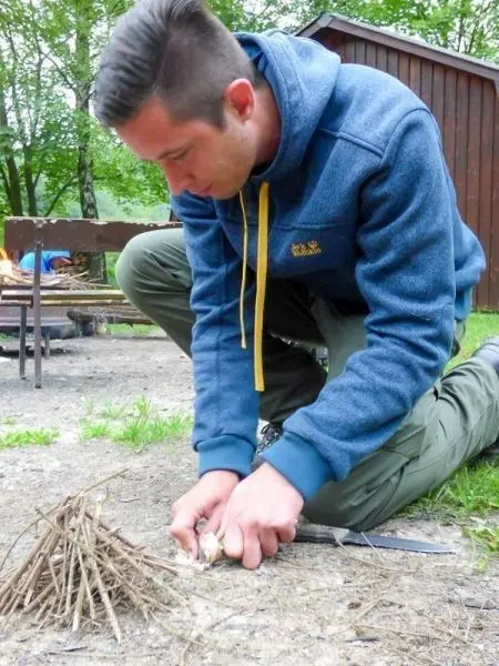 Feuerstahl erzeugt Funken auf Zunderhaufen aus kleinen Ästen