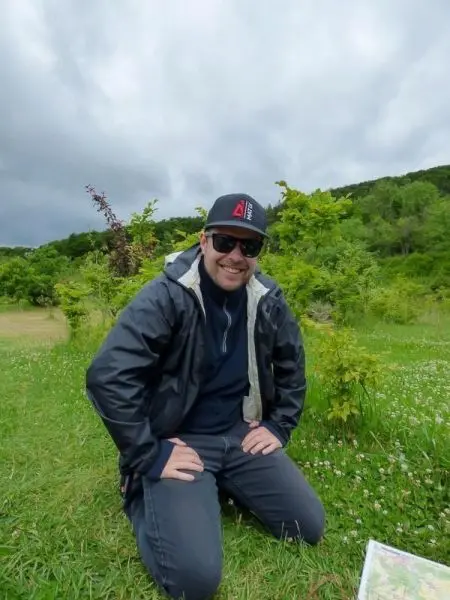 Kneeling auf einer Wiese, hält eine Person eine Karte in der Hand