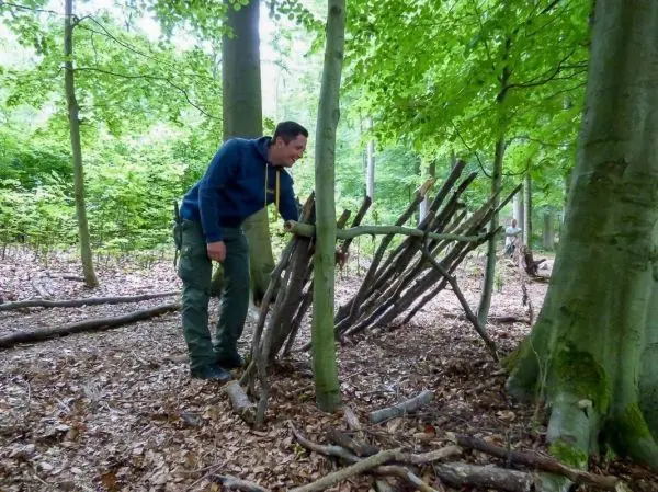 Mann konstruiert eine Holzkonstruktion aus Ästen im Wald