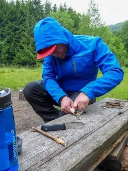 Messer schält Rinde von einem Stock auf einer Holzplatte