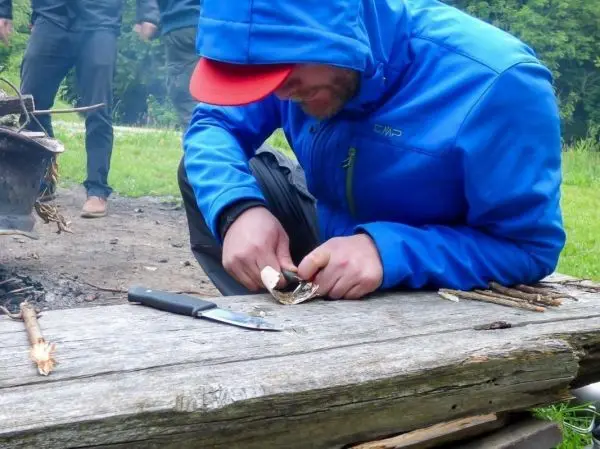 Messer schält Rinde von einem Stock über einer Holzplatte