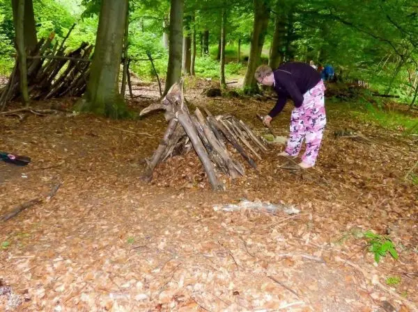 Person baut eine kleine Struktur aus Ästen im Wald