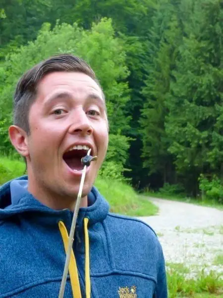 Person hält einen Stock mit einem Gegenstand im Mund