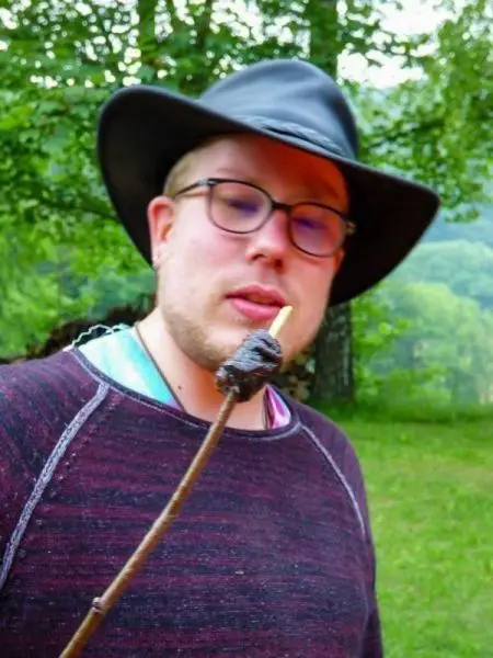 Person hält einen Stock mit einem gegrillten Snack