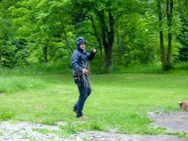 Person trägt Äste und lächelt im Grünen beim Überlebenstraining