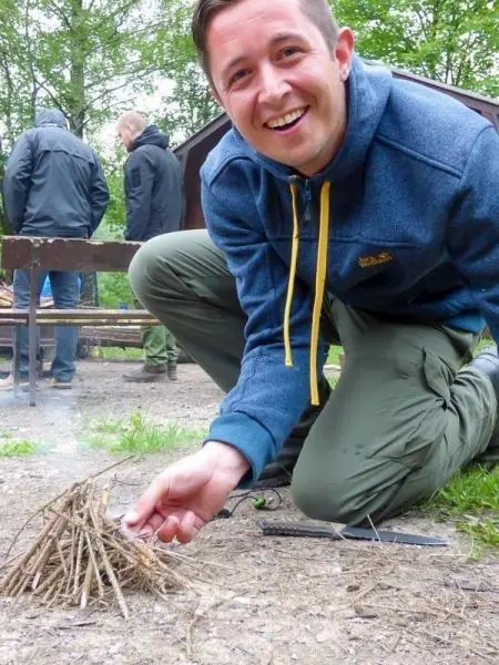 Zunder wird mit einer Hand angezündet, während Rauch aufsteigt