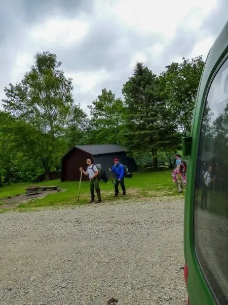 Zwei Personen stehen auf einem Schotterweg und halten Rucksäcke