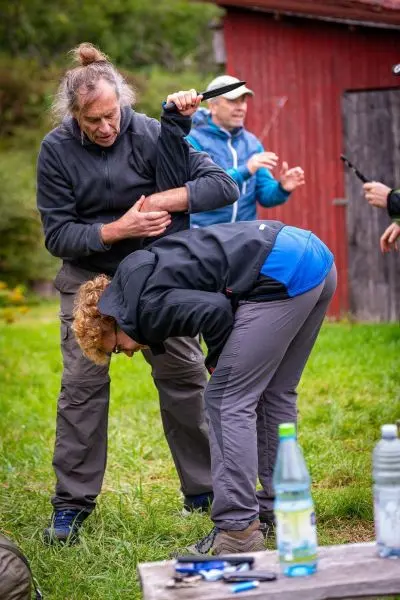 Ein Mann demonstriert eine Erste-Hilfe-Technik an einer Frau im Freien