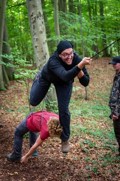 Ein Teilnehmer schwingt an einem Seil über einen anderen, der am Boden hängt