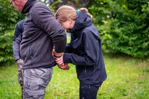 Eine Person befestigt Handfesseln an einem anderen Teilnehmer im Freien