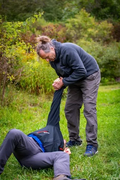 Eine Person hilft einer anderen, die am Boden liegt, indem sie sie am Arm zieht