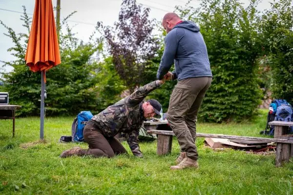 Eine Person hilft einer anderen, die auf dem Boden kniet, beim Aufstehen