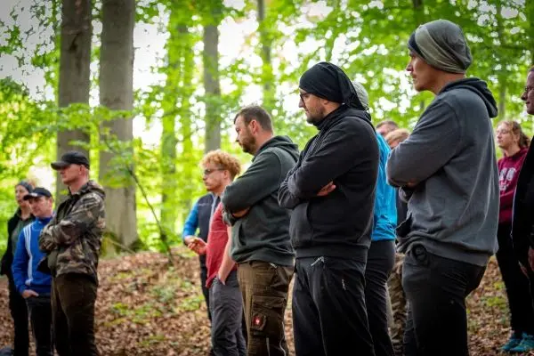 Gruppe hört aufmerksam einer Präsentation im Wald zu