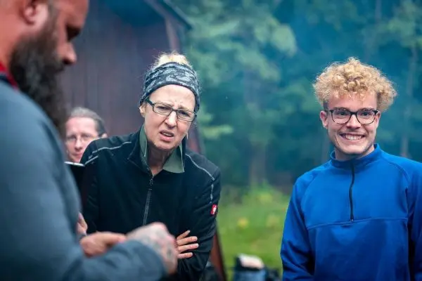 Gruppe um ein Feuer versammelt, diskutiert und beobachtet die Flammen