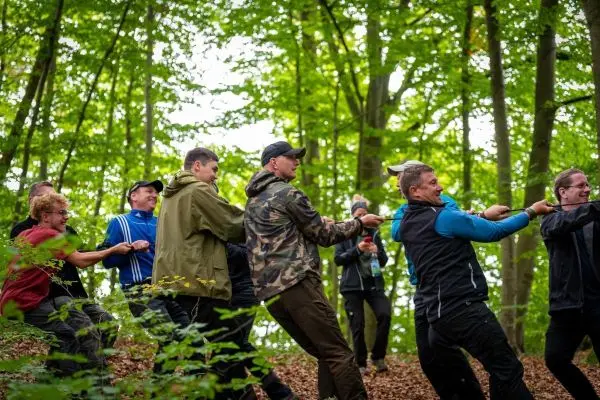 Gruppe zieht gemeinsam an einem Seil im Wald beim Survival Training