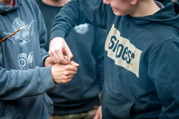 Hände binden eine Schnur um ein Handgelenk