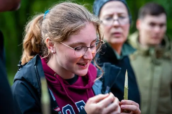 Junge Frau schält einen Zweig mit einem Messer in der Natur