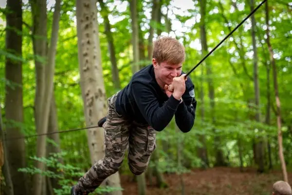 Junge schwingt an einer Seilbrücke zwischen Bäumen im Wald