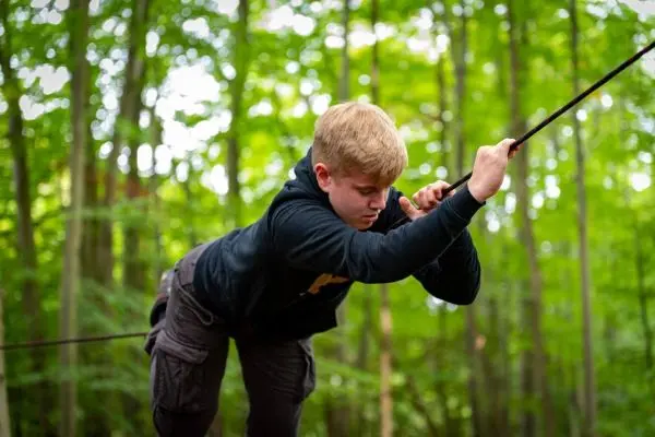 Junge zieht an einem Seil in einem Waldgebiet