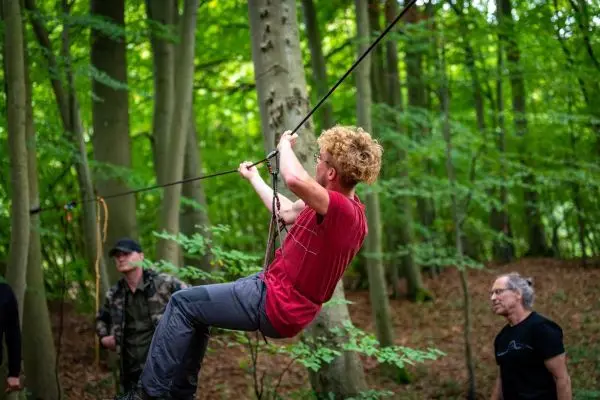 Junger Mann zieht sich an einem Seil durch den Wald