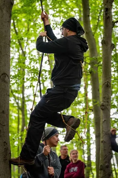 Kletterer nutzt Seil zur Fortbewegung zwischen Bäumen in einem Wald