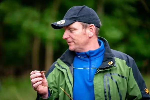 Mann hält einen kleinen Gegenstand in der Hand und betrachtet ihn aufmerksam