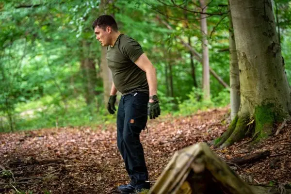 Mann in Outdoor-Bekleidung untersucht den Boden im Wald