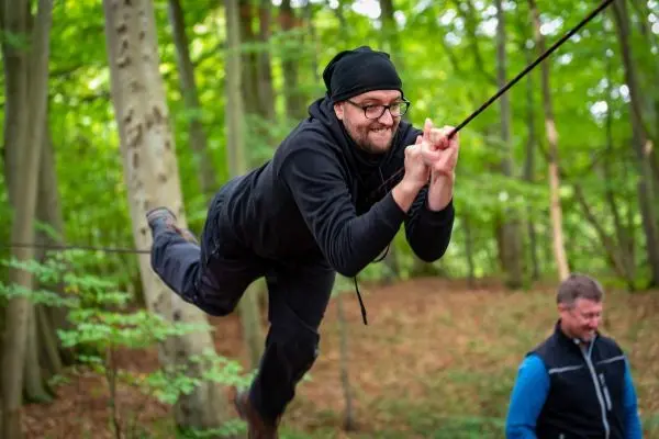 Mann schwingt an einem Seil durch den Wald
