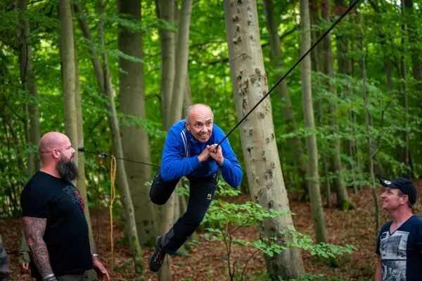 Mann schwingt an Seilbrücke zwischen Bäumen im Wald