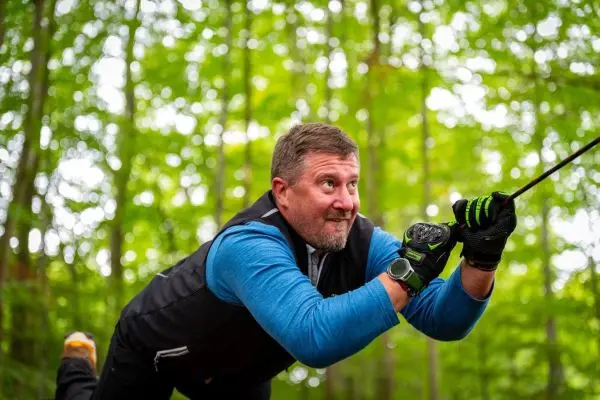 Mann zieht an einem Seil in einem Waldgebiet