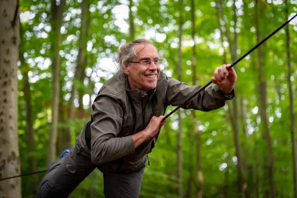 Mann zieht sich an einer Schnur zwischen Bäumen nach vorne