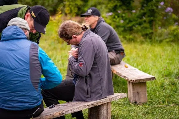 Person arbeitet an Ausrüstung auf einer Holzbank im Freien