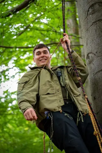 Person hängt an Seil von Baum und lächelt