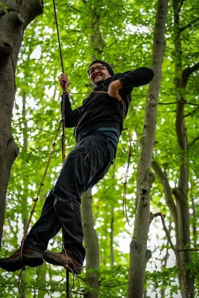 Person klettert mit Seil an Baumstamm hoch