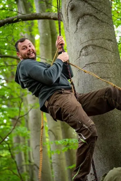 Person schwingt an einem Seil von einem Baum