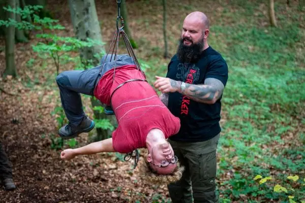 Person sichert hängende Person mit Seil im Wald