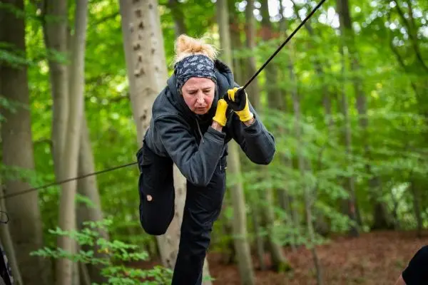Person überquert selbstgebaute Seilbrücke im Wald