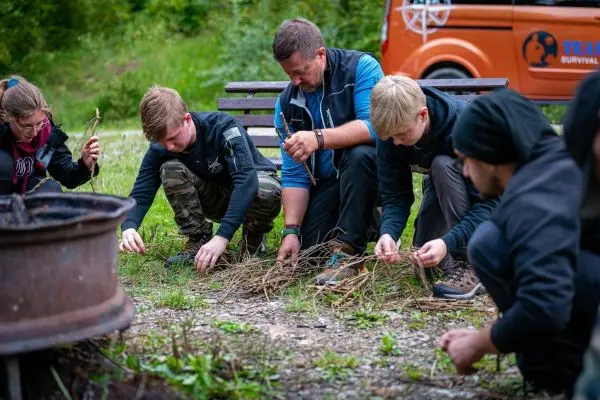 Teilnehmer sammeln Äste und Zunder für ein Feuer