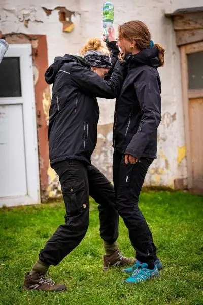 Zwei Personen stehen sich gegenüber und halten eine Flasche hoch