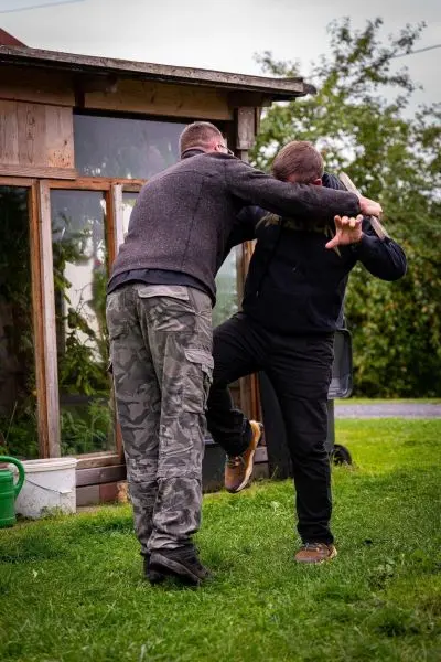 Zwei Personen üben eine Selbstverteidigungstechnik im Freien