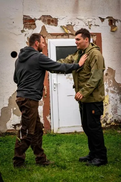 Zwei Personen üben eine Selbstverteidigungstechnik vor einer Wand