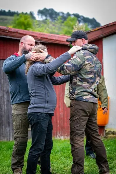 Zwei Personen üben eine Technik zur Kontrolle einer dritten Person im Freien