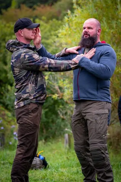 Zwei Personen üben eine Technik zur Selbstverteidigung im Freien