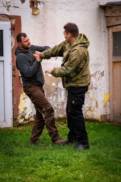 Zwei Personen üben einen Selbstverteidigungsgriff im Freien