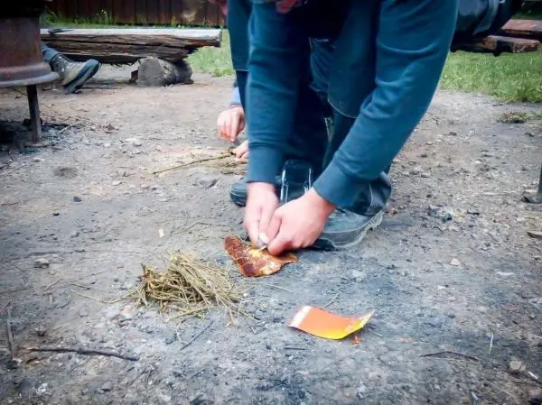 Feuerstahl erzeugt Funken auf Zunder und trockenem Gras