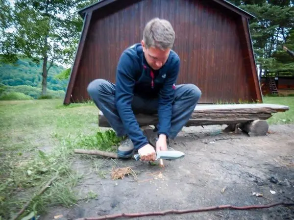 Messer schneidet Zunder auf dem Boden neben einer Holzbank