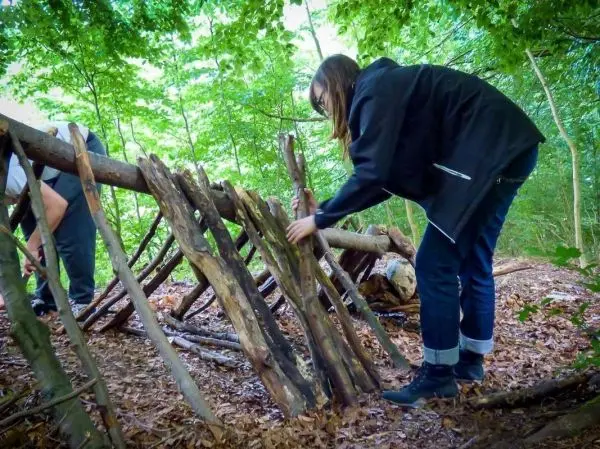 Person baut eine Struktur aus Ästen im Wald