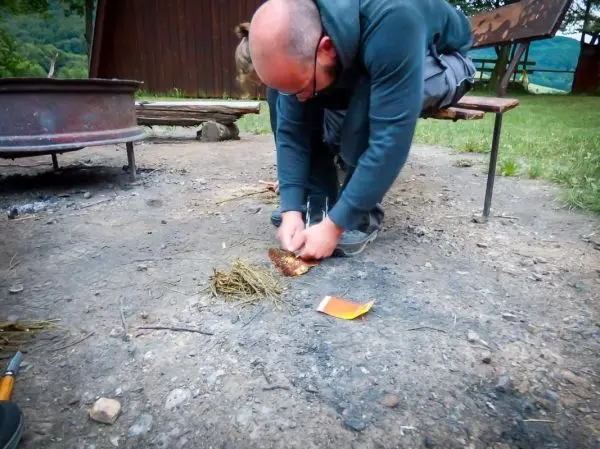 Person bereitet Feuerstelle mit Zunder vor beim Survival Training