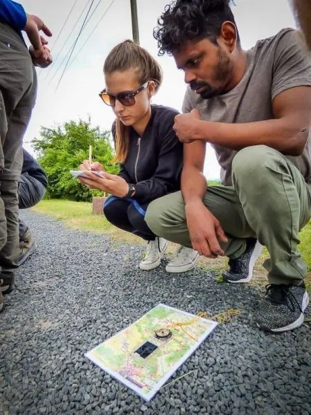 Person notiert auf Karte, während andere zuschauen beim Outdoortraining